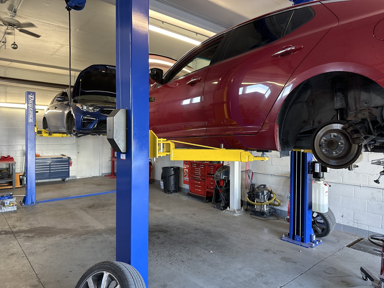 Two vehicles raised on twin-post lifts inside the shop